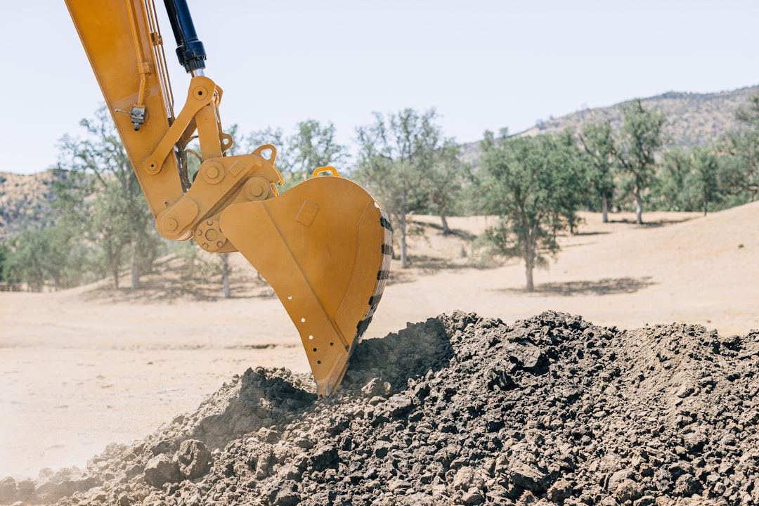 Picture of an excavator hydraulic arm digging into a pile of rock